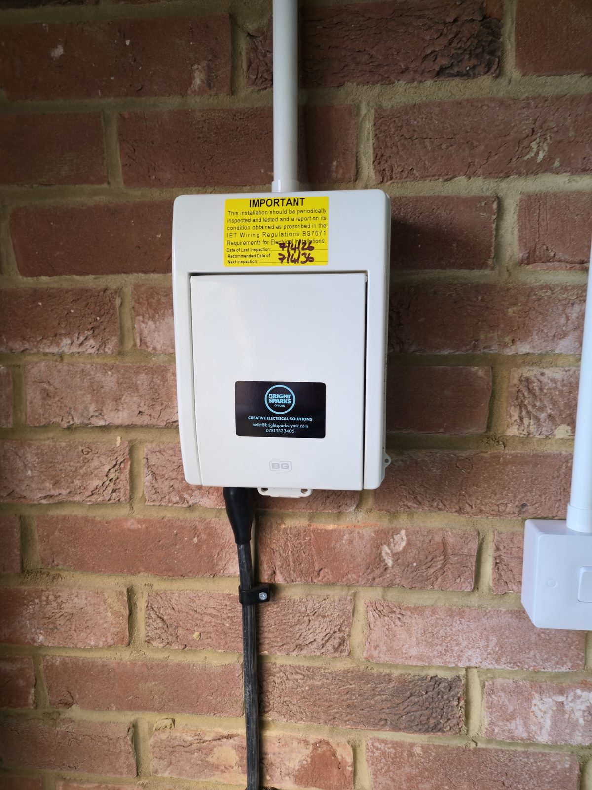 Close-up of the consumer unit with Bright Sparks of York sticker and BS 7671 inspection label
