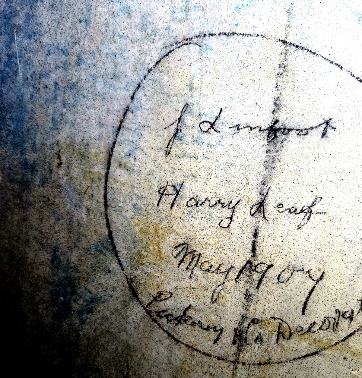 A faint pencil circle on plaster, rotated upright, reading Harry Leaf above a partly legible date and firm name